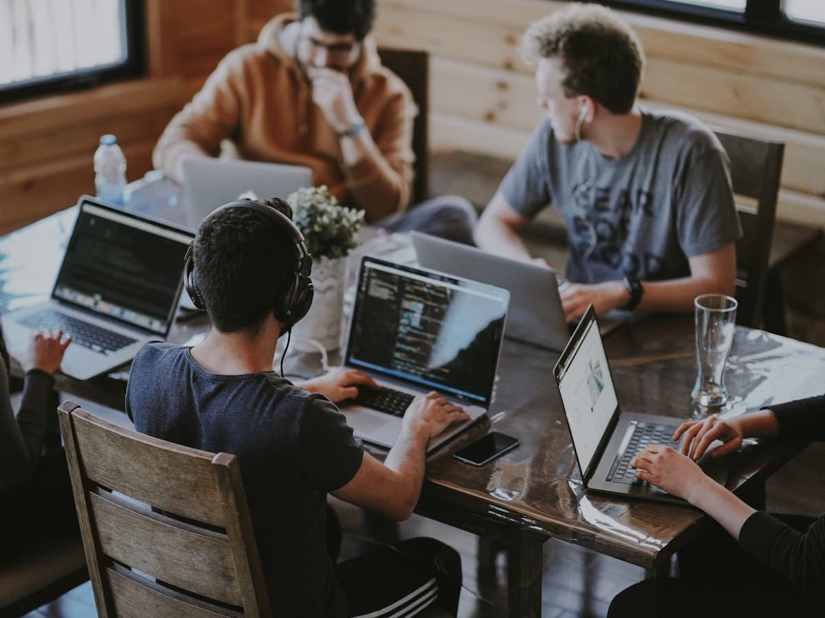Five people building on laptops around a shared wooden table